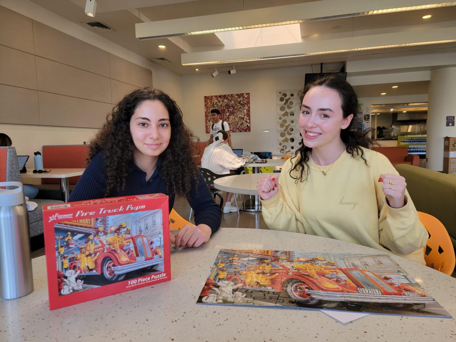 two woman working on a puzzle at a table